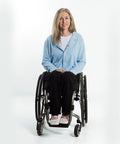 Woman in a wheelchair wearing a light blue cardigan on a white background