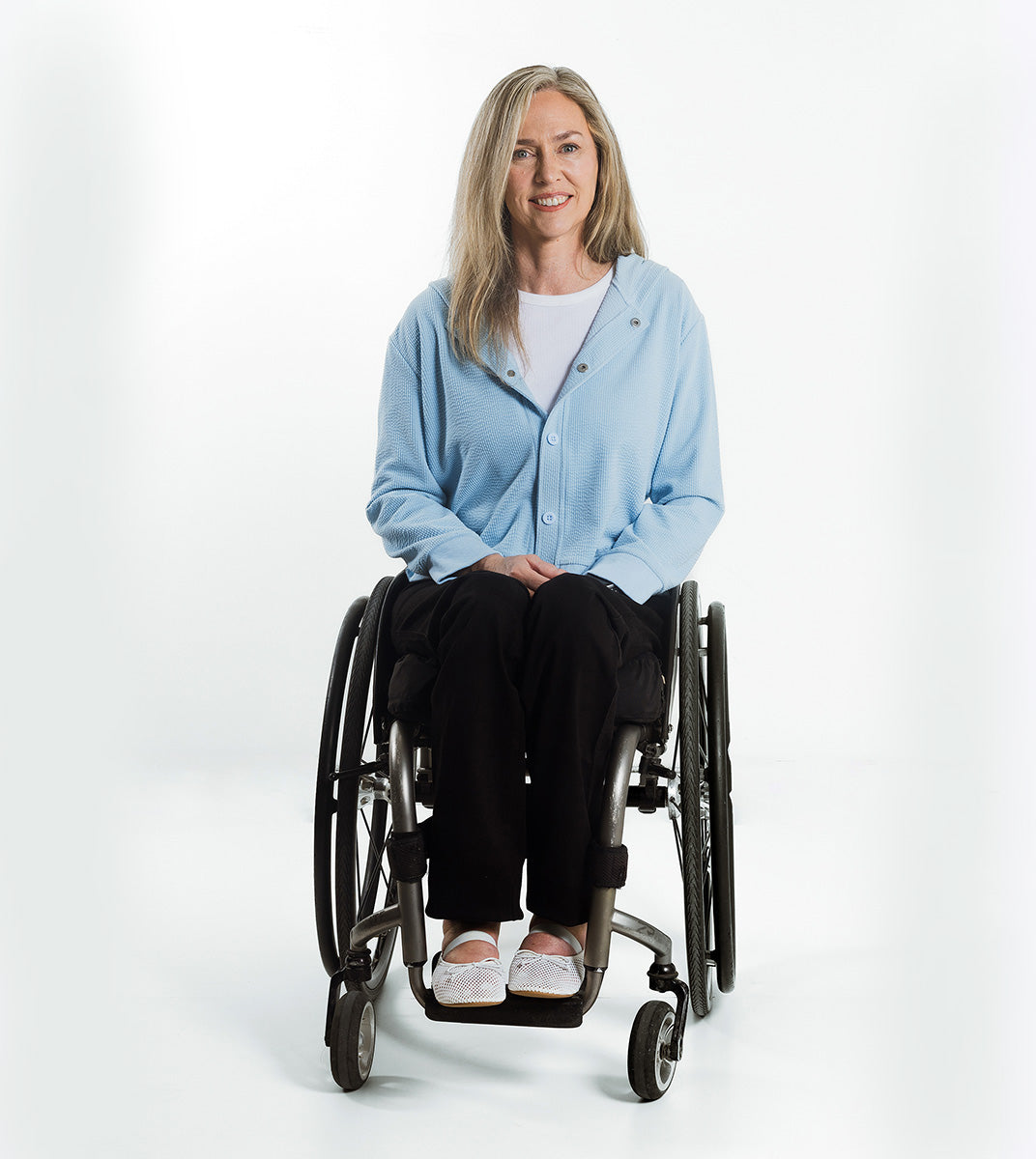 Woman in a wheelchair wearing a light blue cardigan on a white background